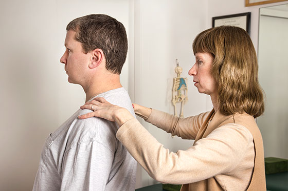 Alexander Technique teacher Laurie Currie working with standing male adult student, in teaching studio in Mahopac, New York, Putnam County.