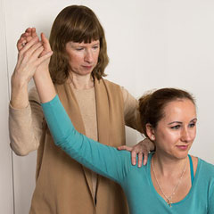 Alexander Technique teacher Laurie Currie working with student's arm while seated in chair. Mahopac, New York